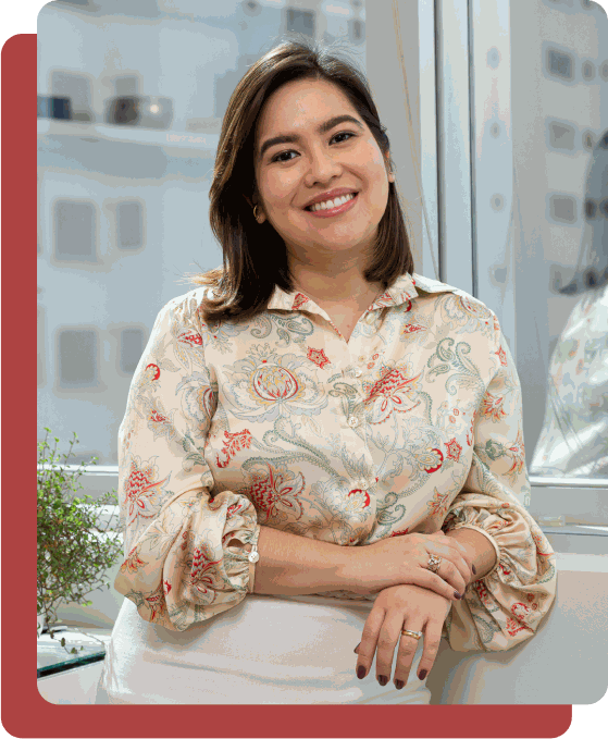 Dra. Paola Teruya sorrindo, apoiada em uma bancada clara do consultório